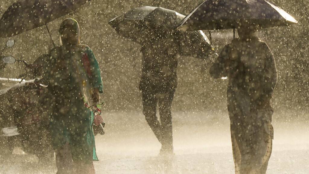 ARCHIV - Menschen laufen während eines plötzlichen Regenschauers mit Regenschirmen in der Hand in Kathmandu. Während der Monsunzeit zwischen Juni und September kommt es häufig zu Überschwemmungen und Erdrutschen. Foto: Skanda Gautam/ZUMA Press Wire/dpa