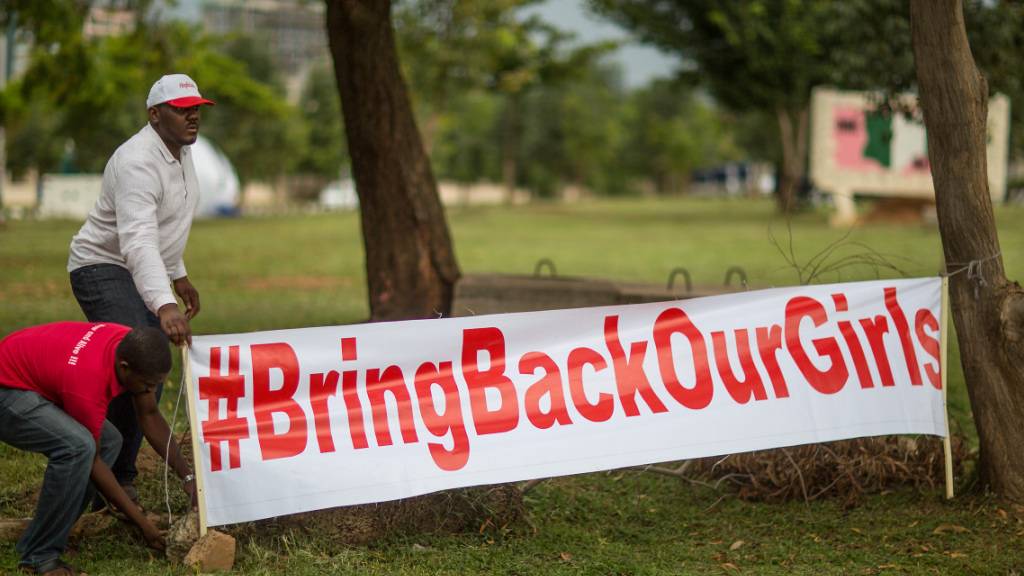 ARCHIV - Aktivisten der Bewegung «Bring back our Girls» (Bringt unsere Mädchen zurück) stellen am 12.06.2014 auf einer Kundgebung in Abuja, Nigeria, ein Transparent mit der Aufschrift «#BringBackOurGirls» auf. Foto: picture alliance / dpa