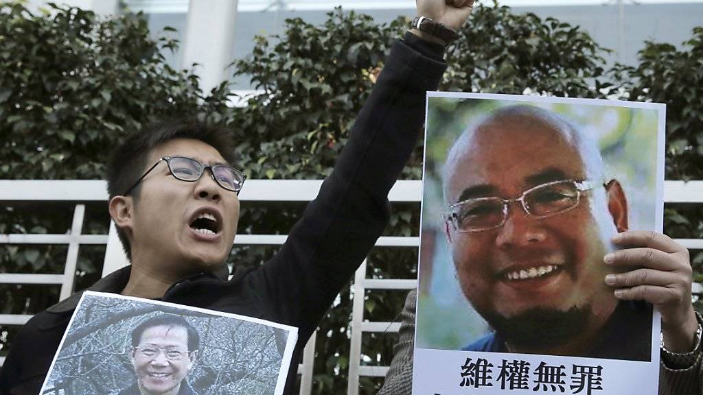 Aktivist in Hongkong mit den Konterfeis der chinesischen Dissidenten Qin Yongmin (l) und Wu Gan
