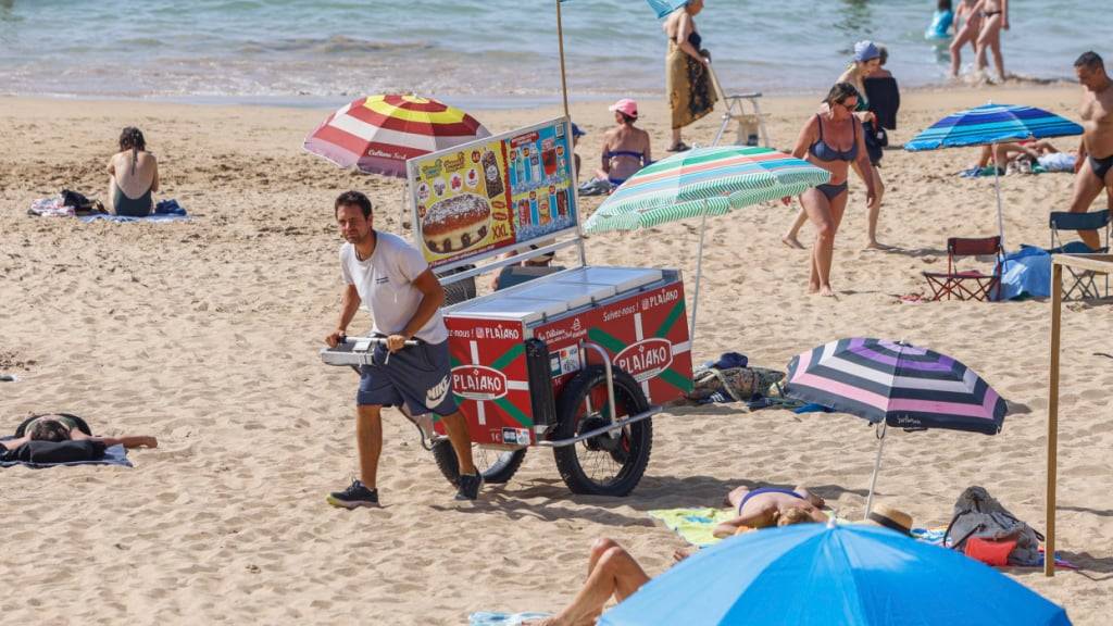 ARCHIV - Ein Strandverkäufer verkauft Eis am Strand. Der beliebte französische Badeort Les Sables- d'Olonne ermahnt Strandgäste neuerdings zu angemessener Kleidung auf seinen Straßen. Foto: Nicolas Mollo/AP/dpa