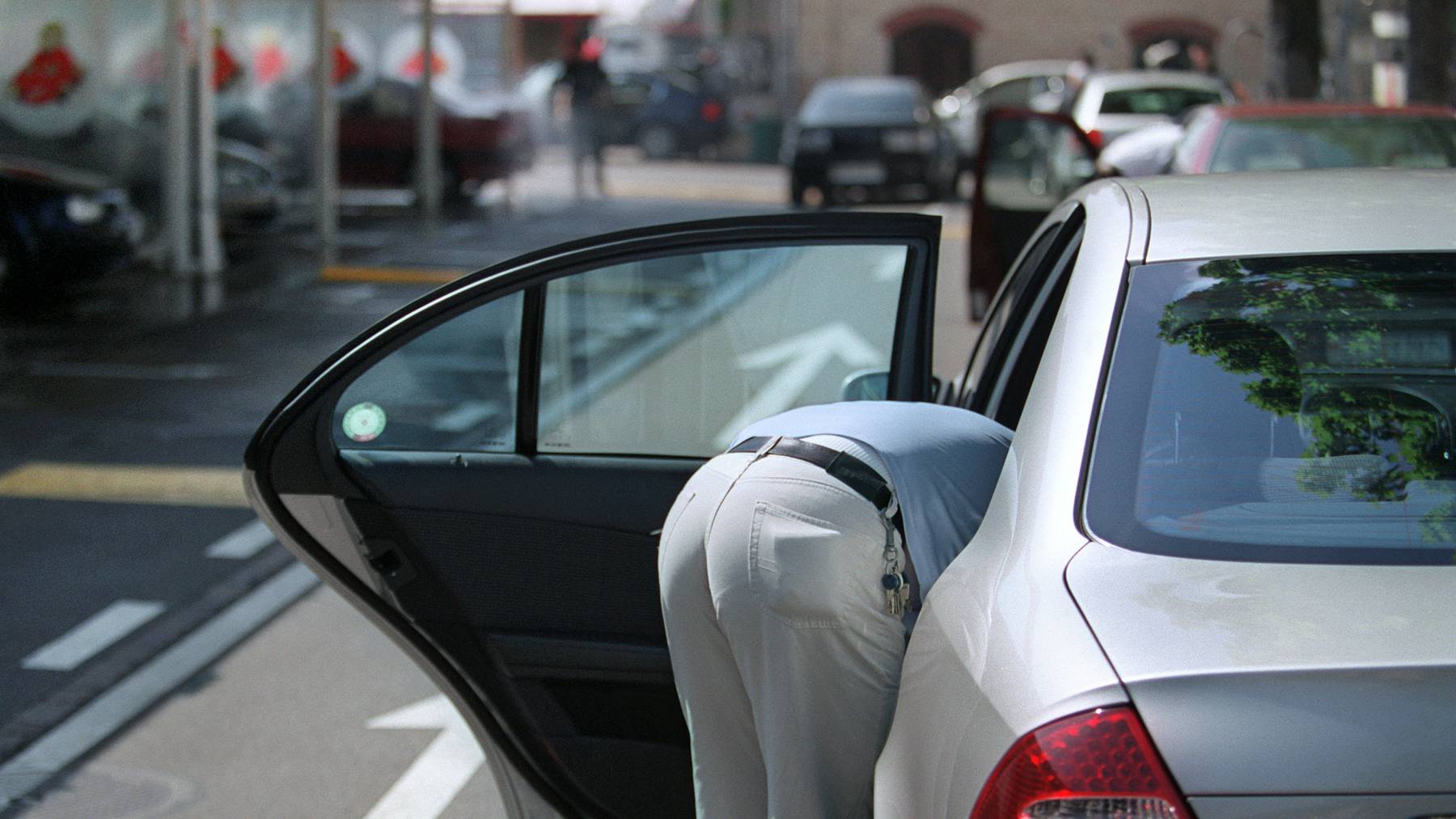 Mann steht mit seinem Auto vor einer Waschanlage