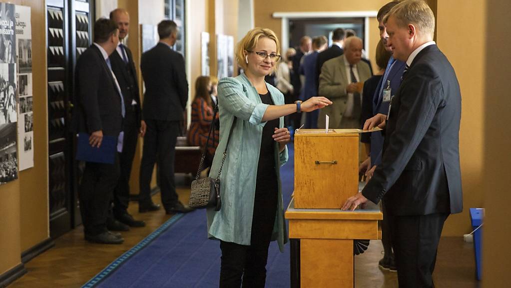 Eine estnische Abgeordnete (M) wirft im estnischen Parlament bei der Wahl über den neuen estnischen Staatspräsidenten ihren Wahlzettel in eine Wahlurne. Einziger Kandidat bei der Abstimmung über das höchste Staatsamt des baltischen EU- und Nato-Landes ist Alar Karis. Foto: Raul Mee/AP/dpa