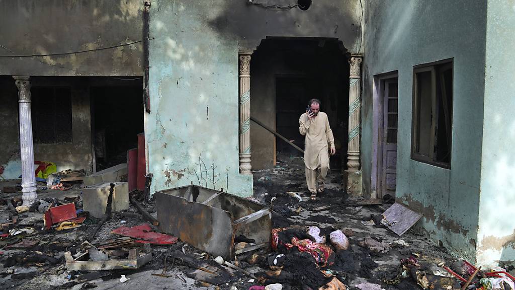 dpatopbilder - Ein Mann telefoniert, als er an einem Haus geht, das von einer wütenden Menschenmenge verwüstet wurde. Der Mob beschuldigte demnach mindestens zwei Christen, den Koran - die heilige Schrift des Islams - entwürdigt zu haben. Was den Gläubigen konkret vorgeworfen wurde, war unklar. Foto: K.M. Chaudary/AP/dpa