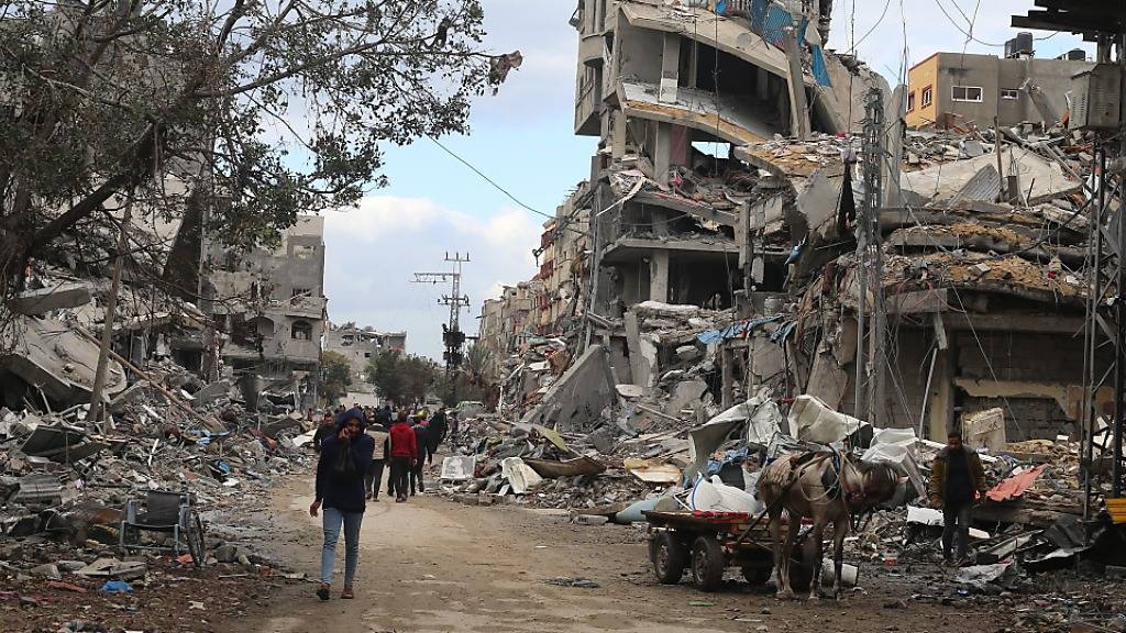 dpatopbilder - Palästinenser gehen am vierten Tag des Waffenstillstandes an Trümmern zerstörter Gebäude vorbei. Foto: Mohammed Alaswad/APA Images via ZUMA Press Wire/dpa