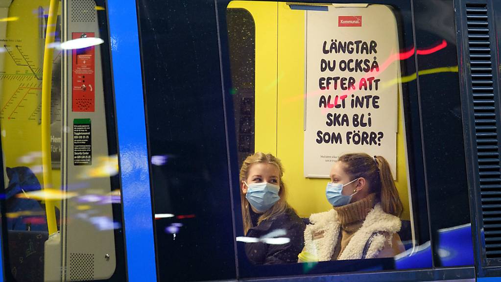 ARCHIV - Zwei Fahrgäste sitzen mit Mund-Nasen-Schutz in einer U-Bahn. Schweden hat auf die Bevölkerung gerechnet derzeit etwa dreimal so hohe Neuinfektionszahlen wie Deutschland - geplante Corona-Lockerungen dürften deshalb in dem skandinavischen Land erst einmal aufgeschoben werden. (zu dpa «Schwedische Gesundheitsbehörde rät von Corona-Lockerungen im April ab») Foto: Jessica Gow/TT NEWS AGENCY/AP/dpa