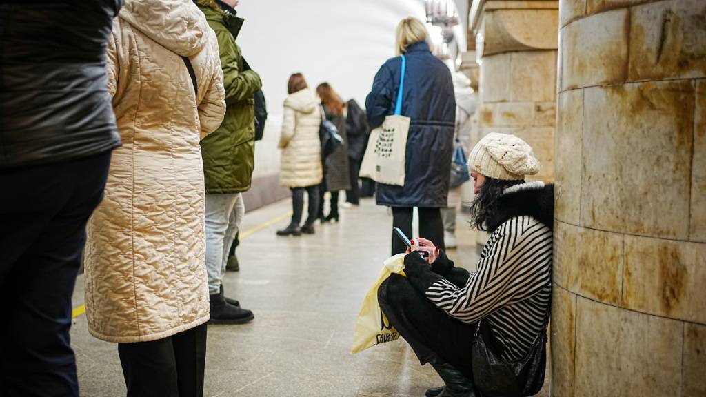 ARCHIV - Passanten stehen und hocken während eines Luftalarms in der Metro in der ukrainischen Hauptstadt Kiew. Am 24.02.2023 jährt sich der russische Angriffskrieg auf die Ukraine das erste Mal. Foto: Kay Nietfeld/dpa