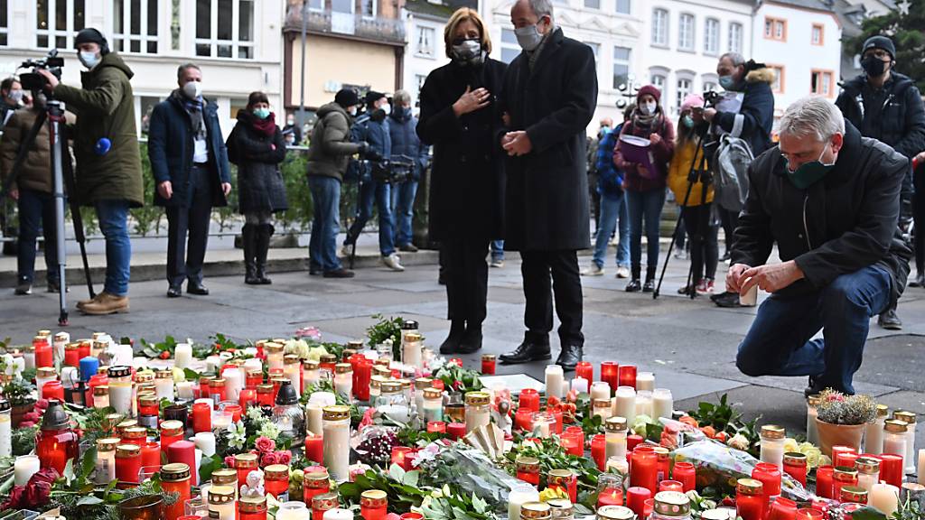 Malu Dreyer (SPD), Ministerpräsidentin von Rheinland-Pfalz, und ihr Ehemann Klaus Jensen stehen vor Blumen und Kerzen, die vor der Porta Nigra im Gedenken der Opfer der Amokfahrt eines 51-jährigen Mannes durch die Innenstadt niedergelegt wurden. Foto: Harald Tittel/dpa