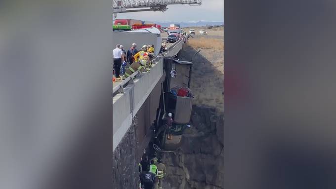 Zwei Personen und zwei Hunde hängen mit Truck von einer Brücke