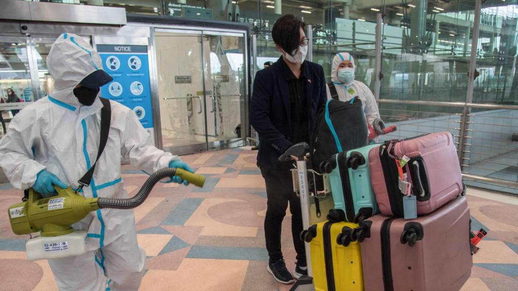 ARCHIV - Ein Flughafenmitarbeiter desinfiziert das Gepäck eines ausländischen Reisenden nach seiner Ankunft. Foto: Peerapon Boonyakiat/SOPA Images via ZUMA Press Wire/dpa