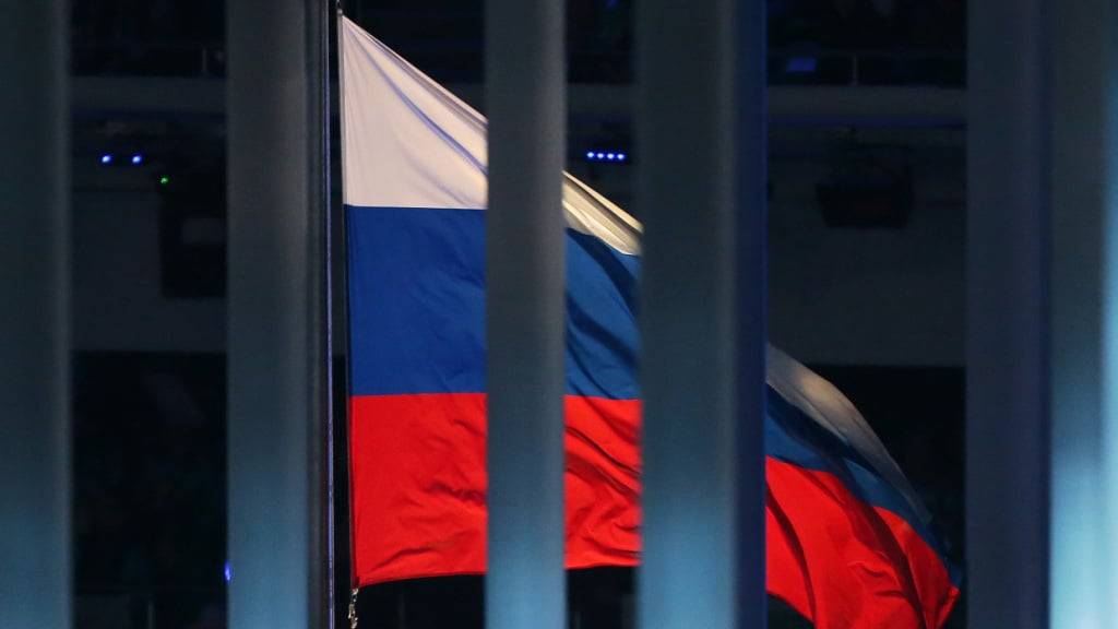ARCHIV - Eine Flagge Russlands weht hinter einem Zaun während der Eröffnungsfeier der Paralympischen Spiele 2014 im Fisht Olympiastadion. Die russische Nationalflagge wird auch bei der am Freitag beginnenden Leichtathletik-WM im Khalifa-Stadion von Doha nicht wehen. Der Weltverband hebt den Bann nicht auf. Foto: Jan Woitas/dpa-Zentralbild/dpa