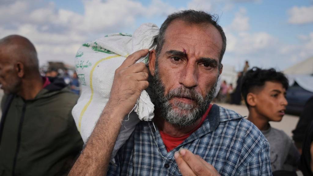 ARCHIV - Palästinenser tragen Taschen mit Lebensmitteln und humanitärer Hilfe, die von der Gaza Humanitarian Foundation, einer von Israel anerkannten und von den USA unterstützten Organisation, bereitgestellt wurden. Foto: Abdel Kareem Hana/AP/dpa