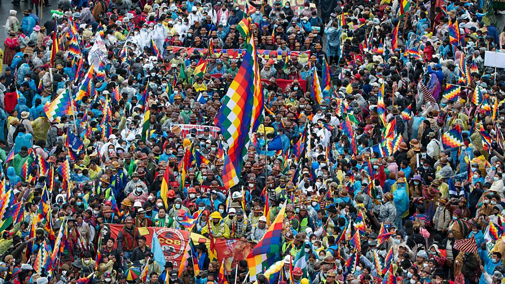 Zahlreiche Menschen schwenken Fahnen während einer Kundgebung in der Innenstadt von La Paz. Am Montag sind unter der Anführung von dem ehemaligen Präsidenten Evo Morales Tausende Menschen nach einem Marsch durch Bolivien in La Paz eingetroffen. Foto: Radoslaw Czajkowski/dpa