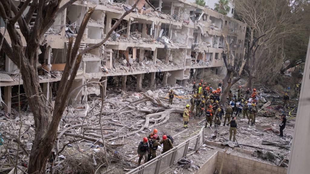 Rettungskräfte versammeln sich nach iranischen Angriffen auf Israel um ein zerstörtes Gebäude. Foto: Ilia Yefimovich/dpa