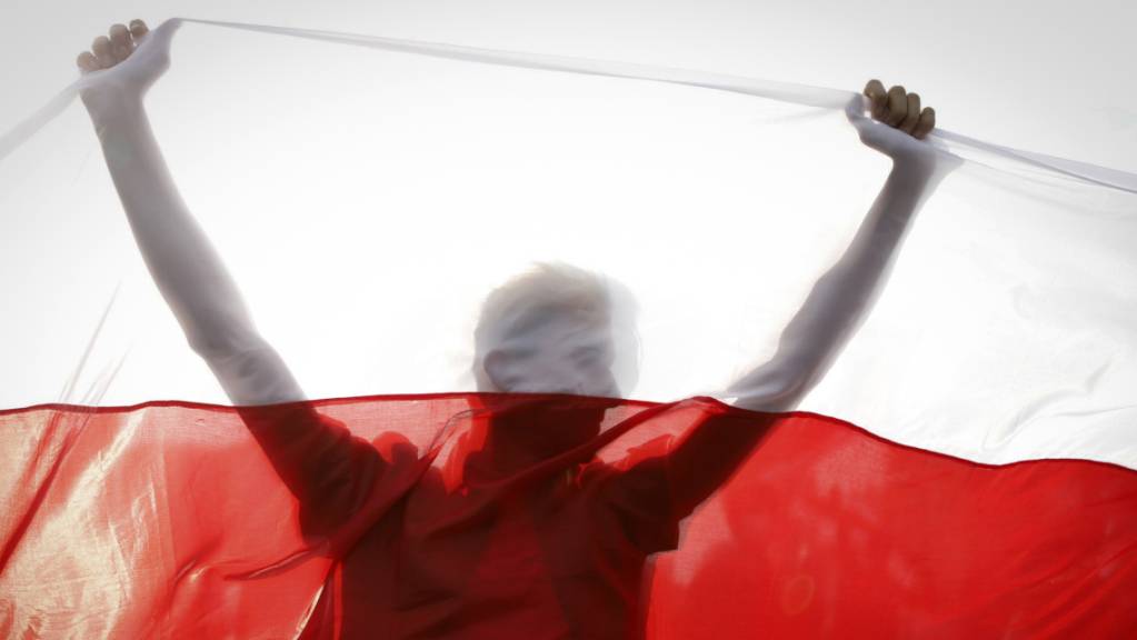 Ein Demonstrant hält eine historische belarussische Fahne. Foto: Uncredited/AP/dpa