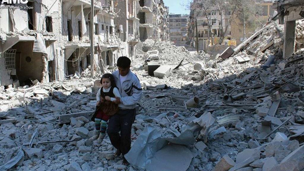 Mann mit Kind inmitten von zerstörten Häusern in Aleppo (Archiv).
