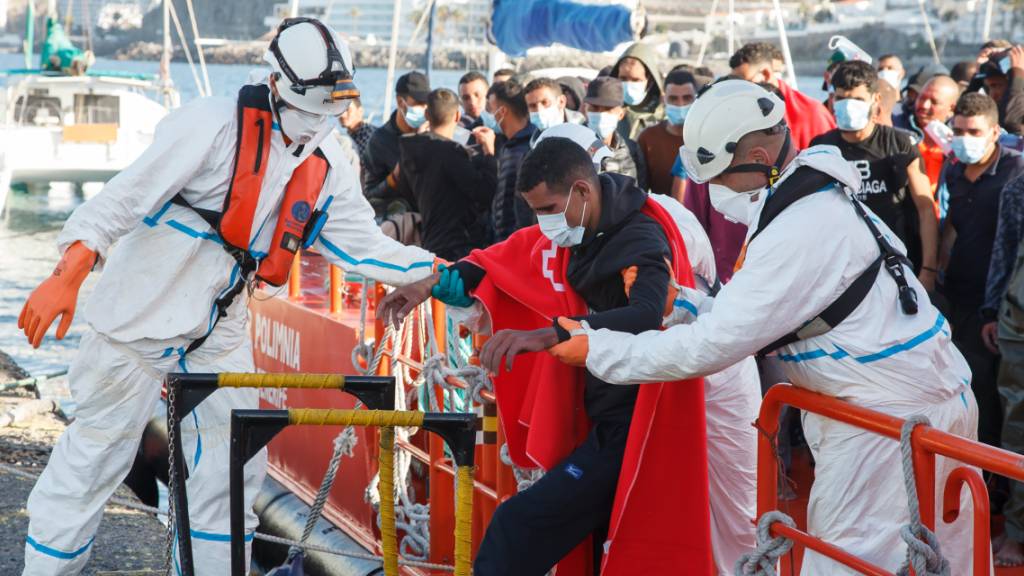 Mitarbeiter des Roten Kreuzes in Schutzkleidung helfen bei der Überführung von Migranten aufs Festland. Auf den Kanarischen Inseln vor der Westküste Afrikas sind am Freitag (09.10.20) mehr als 700 Migranten in 22 Booten angekommen. Das war die höchste Tageszahl seit der Migrationskrise 2006. Foto: Europa Press/EUROPA PRESS/dpa