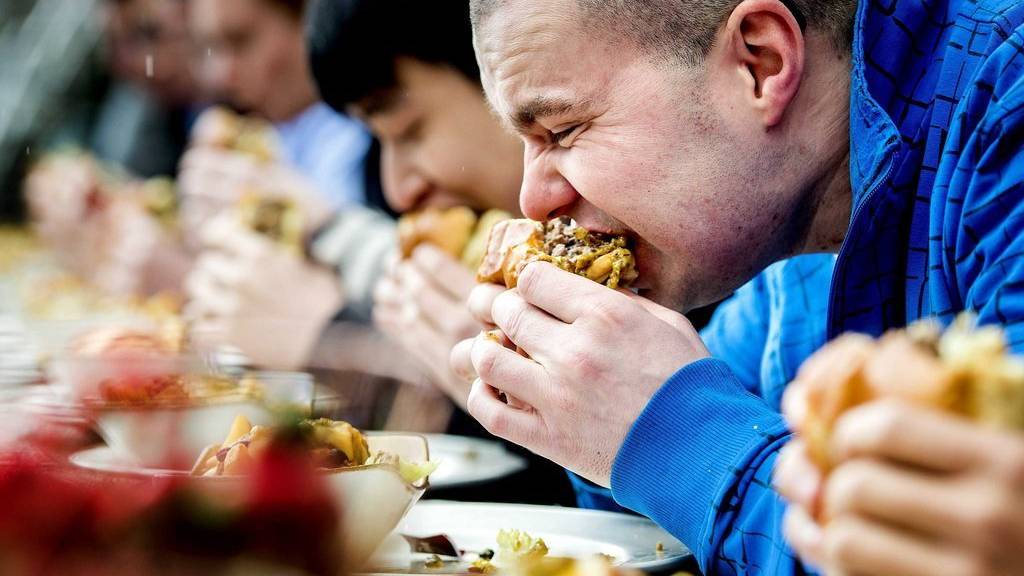 epa05179978 Participants eat burgers during a burger-eating competition on the occasion of National Chili Day in Amsterdam, The Netherlands, 25 February 2016. The person who eats the burger as first wins the price of free burgers for one a year long in the Amsterdam Hard Rock Cafe.  EPA/KOEN VAN WEEL