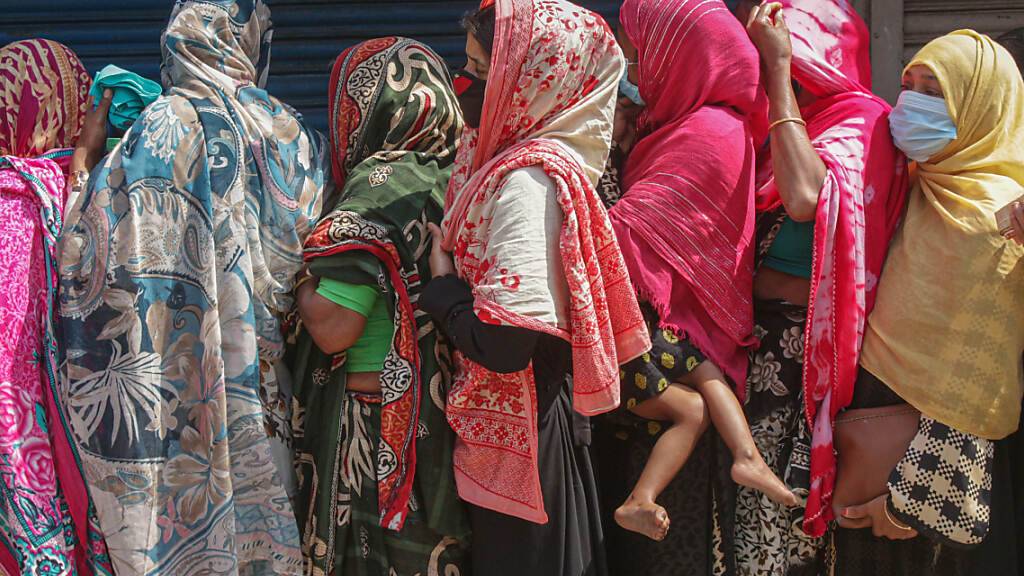 Frauen stehen gedrängt in einer Schlange, um Reis und Mehl auf dem offenen Markt zu kaufen. Ein landesweiter Lockdown hat für sieben Tage begonnen. Foto: Md Rafayat Haque Khan/ZUMA Wire/dpa