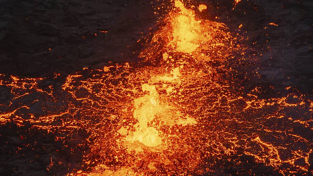 dpatopbilder - Aus Felsspalten tritt glühende Lava aus einem Vulkan in Grindavik auf Island. Foto: Marco di Marco/AP/dpa