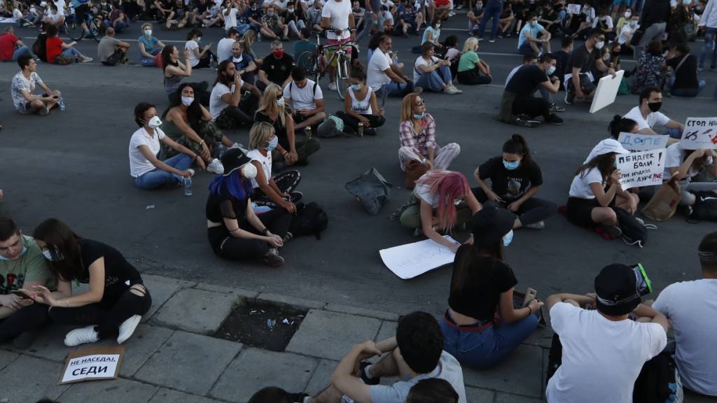 Demonstranten in Belgrad protestieren sitzend gegen die von Präsident Aleksandar Vucic verhängten Corona-Restriktionen. (Foto: Darko Vojinovic/AP/KEYSTONE-SDA)