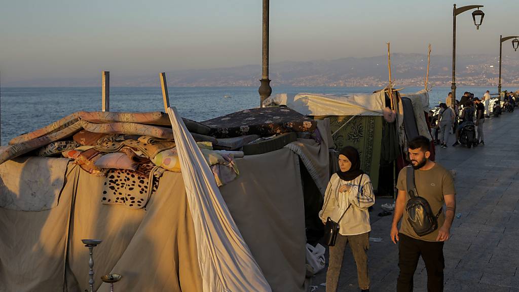 Menschen gehen an Zelten vorbei, die von vertriebenen Familien, die vor den israelischen Luftangriffen im Süden und in Dahieh geflohen sind, an der Corniche von Beirut aufgestellt wurden. Foto: Bilal Hussein/AP