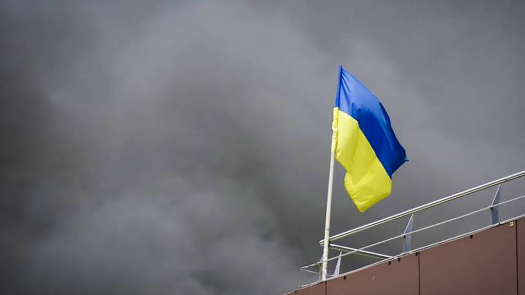 HANDOUT - Auf diesem von der Regionalverwaltung Dnipropetrowsk veröffentlichten Foto weht die ukrainische Flagge, während nach einem russischen Raketenangriff Rauch aufsteigt. Foto: Uncredited/Dnipro Regional Administration/AP/dpa