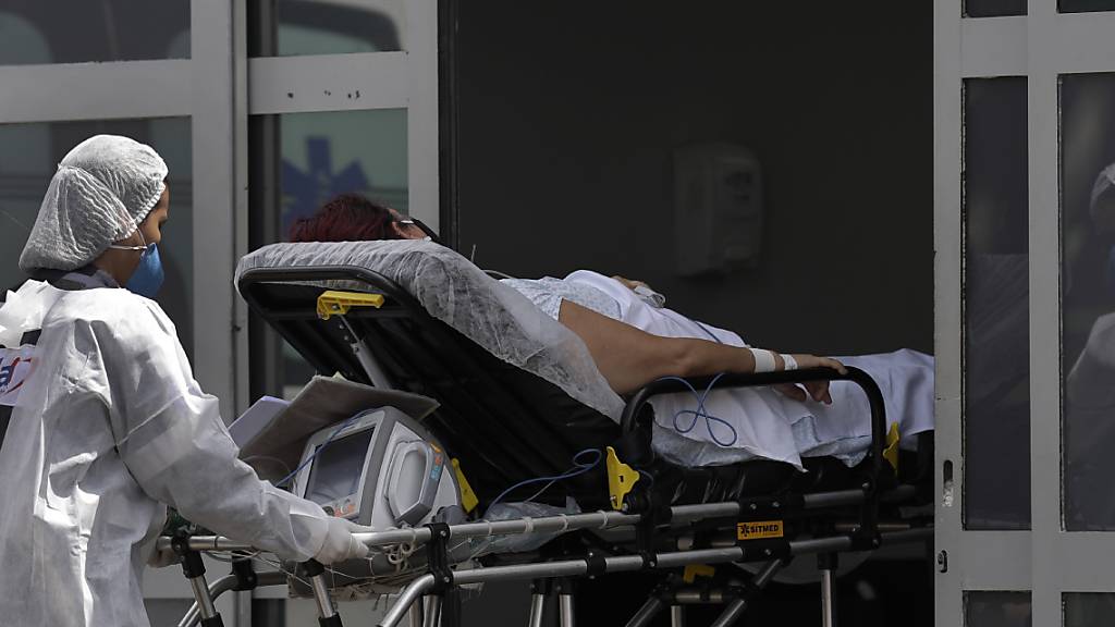 Ein Mitarbeiter des Gesundheitswesens schiebt einen Patienten mit Verdacht auf Covid-19 aus einem Krankenwagen in das öffentliche Krankenhaus HRAN in Brasilia. Foto: Eraldo Peres/AP/dpa