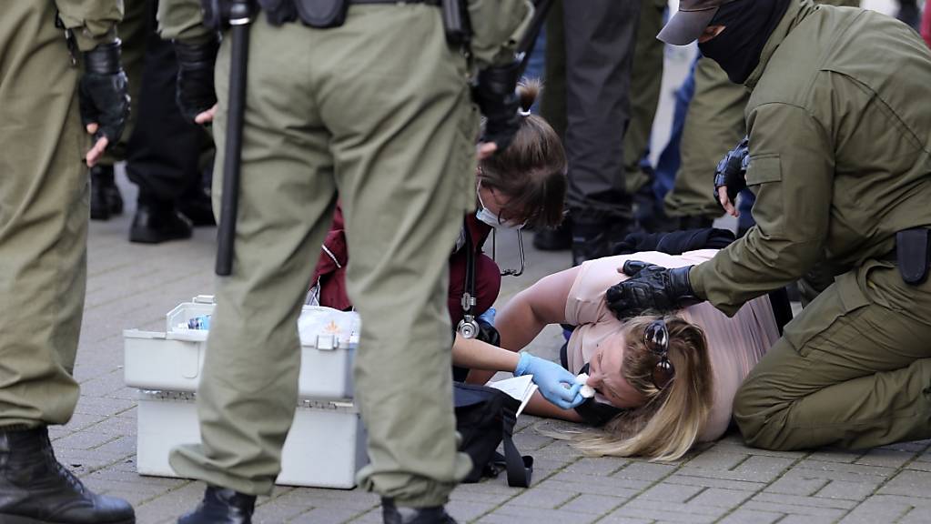 Eine Notärztin kümmert sich am Rande einer Demonstration gegen die Wahlergebnisse in Belarus um eine verletzte Frau, die neben Polizeibeamten auf dem Boden liegt. Foto: Uncredited/TUT.by/dpa