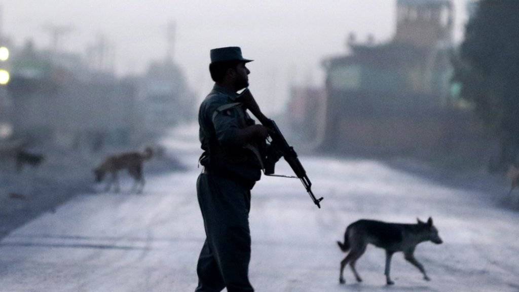 Ein afghanischer Polizist sichert in Kabul die Strasse, die zum Tatort führt: Die Taliban hatten bei einem Hotel einen Anschlag verübt - drei Kämpfer starben.