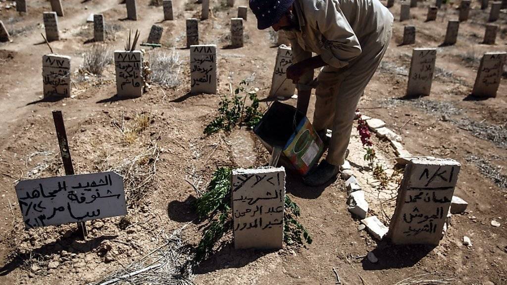 Ein Mann wässert das Grab eines mutmasslichen Opfers eines Chemieangriffs in Syrien.