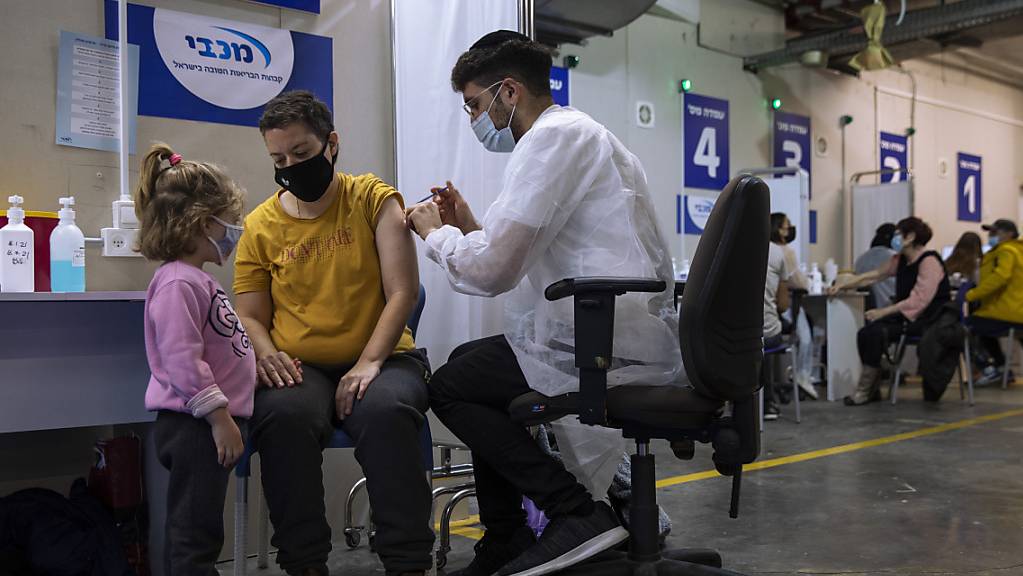 Eine israelische Frau bekommt von einer medizinischen Fachkraft in einem Impfzentrum eine Impfdosis mit dem Corona-Impfstoff von Biontech/Pfizer.