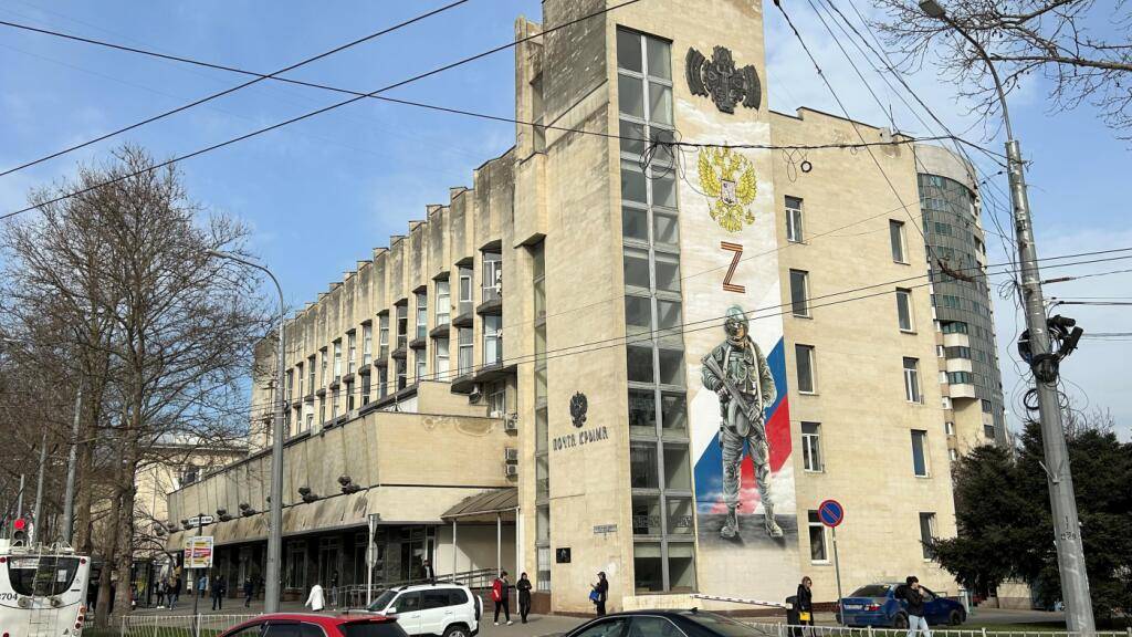 ARCHIV - An der Fassade der Hauptpost im Zentrum der Hauptstadt der Schwarzmeer-Halbinsel Krim erinnert ein großes Wandbild an die «militärische Spezialoperation», wie Russland seinen Krieg gegen die Ukraine nennt. Foto: Ulf Mauder/dpa