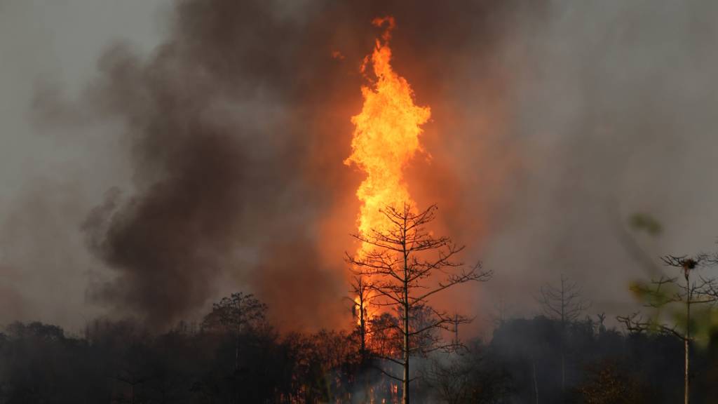 Flammen lodern über einem Ölfeld, nachdem unkontrolliert Gas aus einem Bohrloch geströmt ist und sich entzündet hat. Foto: Str./XinHua/dpa