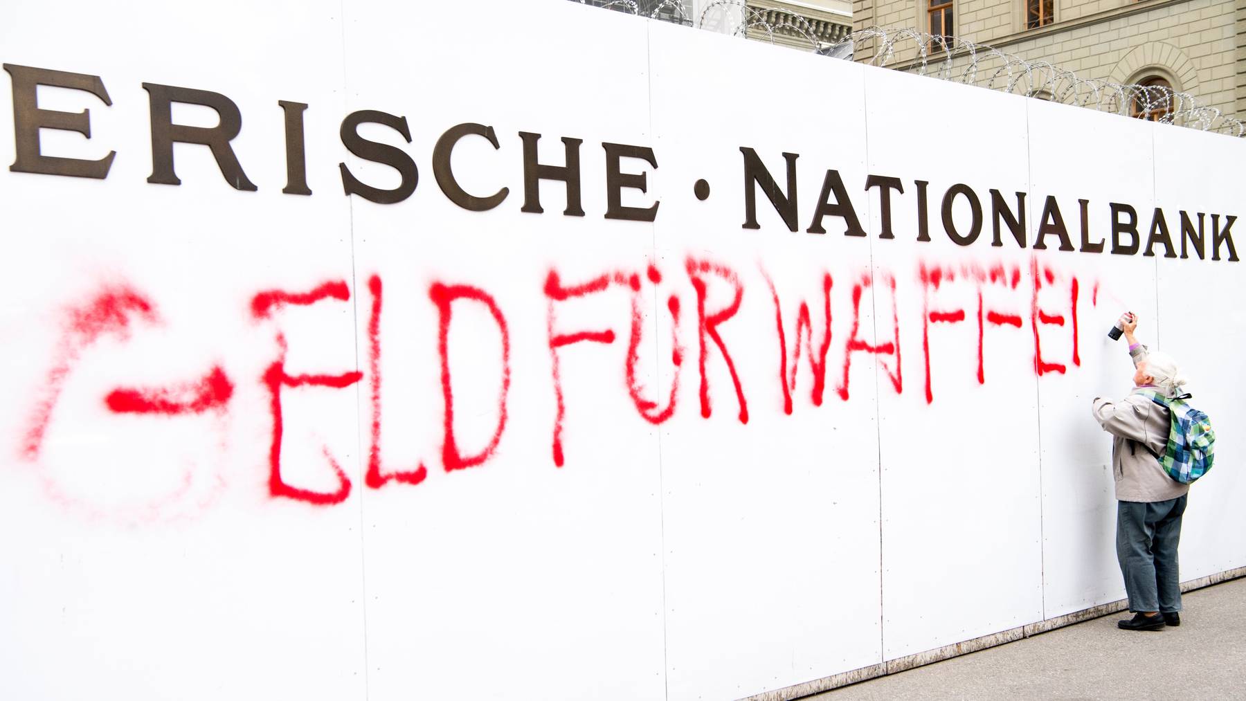 Zum Sammelstart besprayt in Bern eine Friedensaktivistin der Gsoa eine Baustellenwand der Schweizerischen Nationalbank.