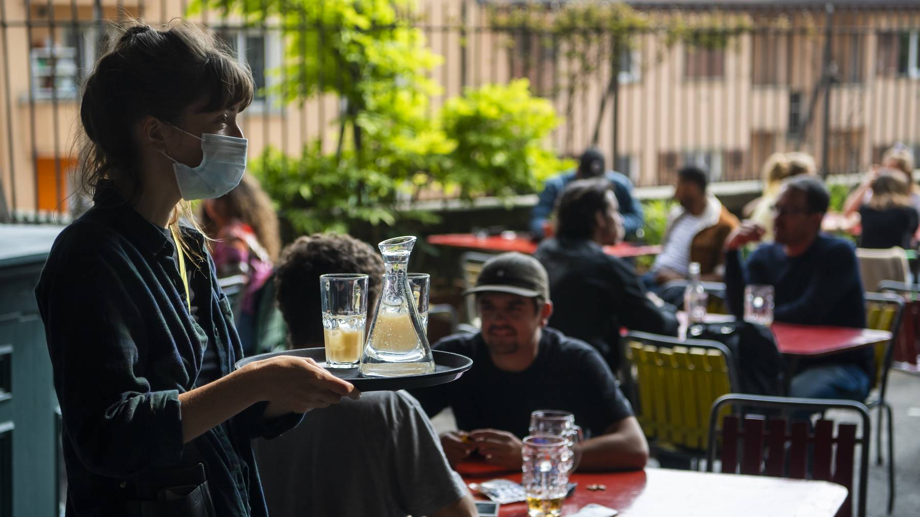 Eine Kellnerin mit Maske bedient Kunden in einem Gastrobetrieb in Lausanne. (Symbolbild)