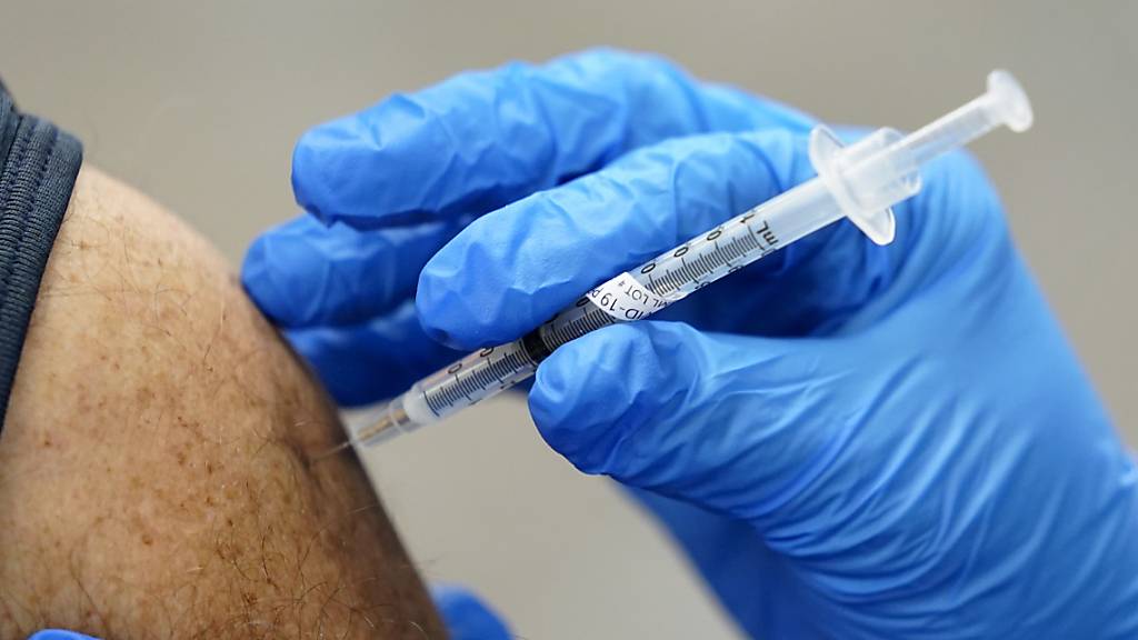 ARCHIV - Ein Mitarbeiter des Gesundheitswesens wird ein zweites Mal mit dem Impfstoff von Pfizer/Biontech geimpft. Foto: Paul Sancya/AP/dpa