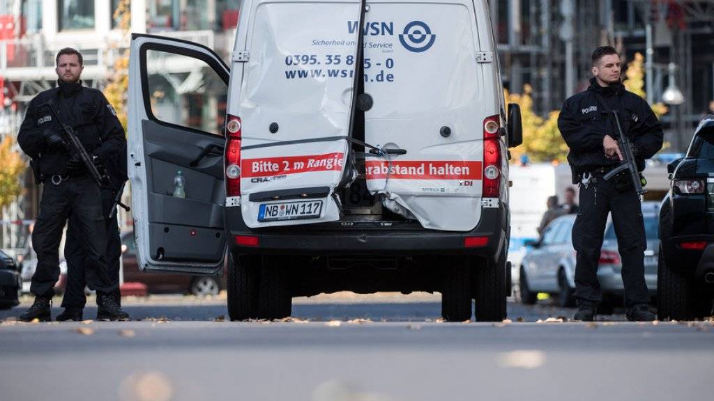 Polizisten mit Maschinenpistolen sichern in Berlin den  Geldtransporter mit aufgebrochenen Türen.