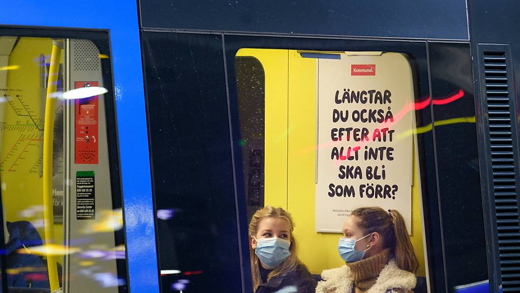 ARCHIV - Zwei junge Frauen sitzen mit Mund-Nasen-Schutz in Stockholm in einer U-Bahn. Aufgrund der aktuellen Lage durch die Omikron-Variante werden auch in Schweden die Corona-Maßnahmen verschärft. Foto: Jessica Gow/TT NEWS AGENCY/AP/dpa