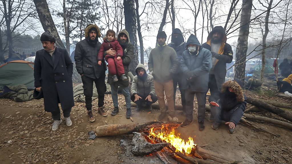 ARCHIV - Migranten versammeln sich an der belarussisch-polnischen Grenze an einem Feuer, um sich zu wärmen. (Archivbild) Foto: Ramil Nasibulin/BelTA/AP/dpa
