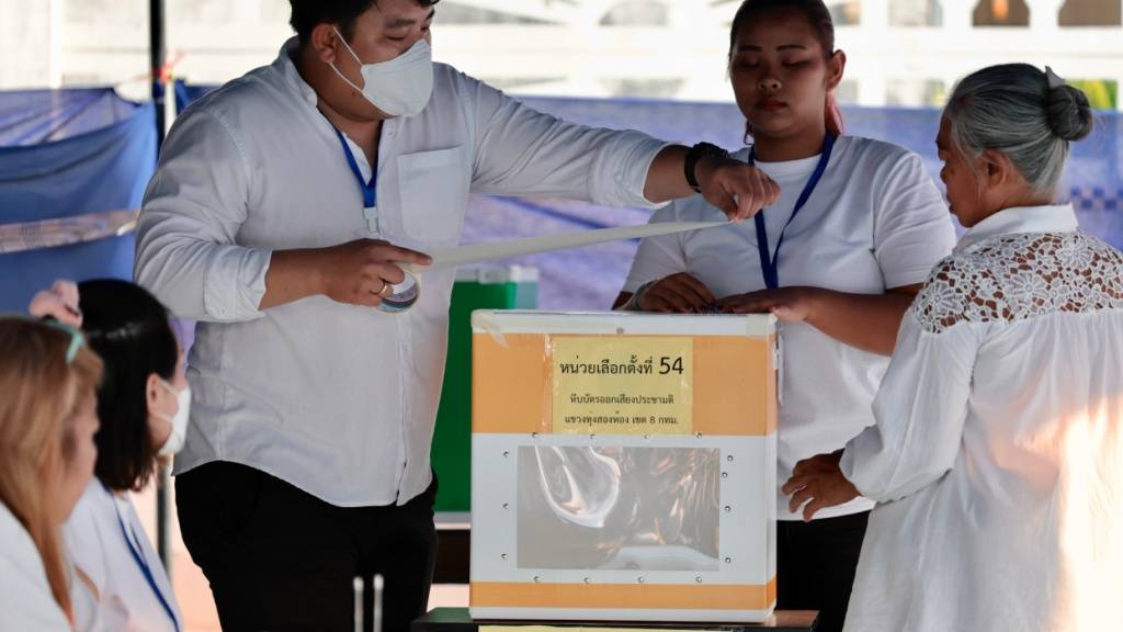 Polizeibeamte und Freiwillige versiegeln eine Wahlurne in einem Wahllokal vor Beginn der Wahlen. Thailand stimmt über ein neues Parlament ab. Dabei geht es um die 500 Sitze im Unterhaus. Gleichzeitig werden die 53 Millionen Wahlberechtigten in einem Referendum gefragt, ob ein Prozess zur Ausarbeitung einer neuen Verfassung beginnen soll. Foto: Wason Wanichakorn/AP/dpa