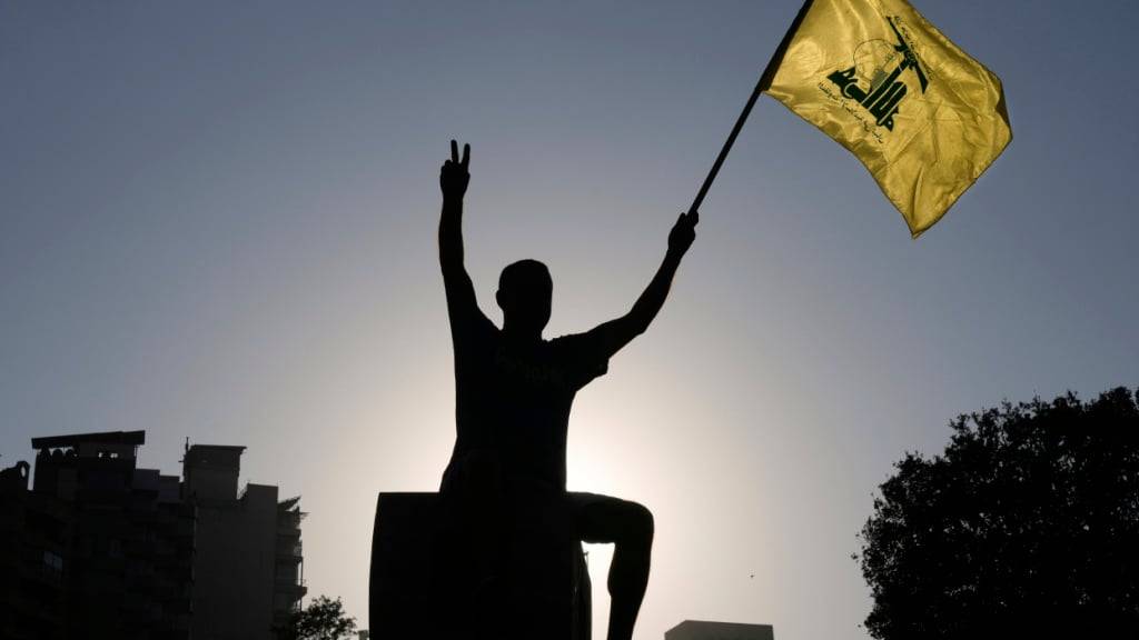 dpatopbilder - Ein Hisbollah-Anhänger hält eine Hisbollah-Fahne vor dem Sitz der UN-Wirtschafts- und Sozialkommission für Westasien (ESCWA) während einer Demonstration gegen den israelischen Krieg und die angebliche Aushungerung der Zivilbevölkerung im Gazastreifen hoch. Foto: Bilal Hussein/AP/dpa