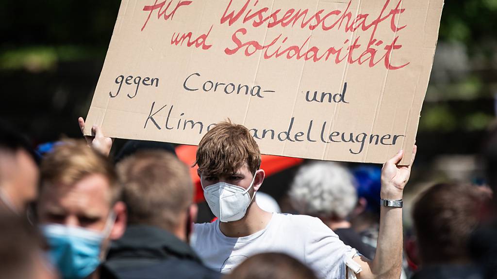 «Für Wissenschaft und Solidarität - Gegen Corona- und Klimawandelleugner» steht auf dem Schild eines Demonstranten, der an einer Gegen-Demonstration teilnimmt, die sich gegen die Demo der Initiative «Querdenken» richtet. Foto: Christoph Schmidt/dpa