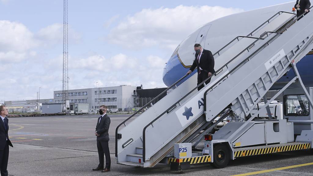 Mike Pompeo, Außenminister der USA, trägt einen Mund-Nasenschutz, während er nach seiner Landung aus der Maschine steigt und von Carla Sands (l), US-Botschafterin in Dänemark, begrüßt wird. Foto: Thibault Savary/pool AFP/AP/dpa