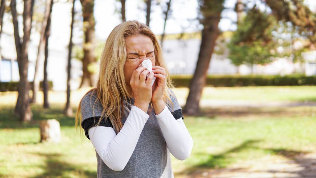 Frau leidet an Pollenallergie und putzt sich die Nase