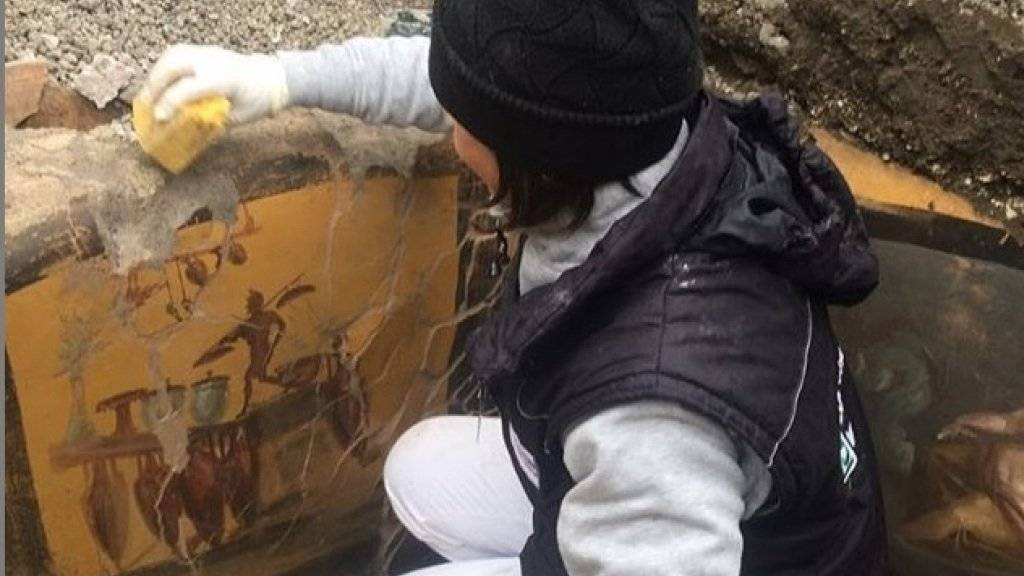Eine Archäologin legt Fresken frei, welche die Theke eines Thermopoliums - eines Strassenimbisses - in Pompeji verzieren. Die zerfallene Stätte ist zwar saniert worden, aber ein Drittel der Stadt ist noch nicht freigelegt. (Instagram Massimo Osanna)