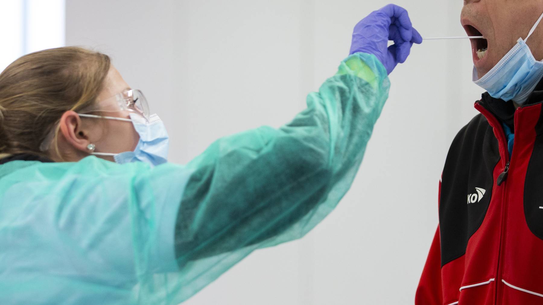 Eine Mitarbeiterin eines mobilen Coronavirus Testcenters in Bern macht einen Abstrich bei einem Mann.