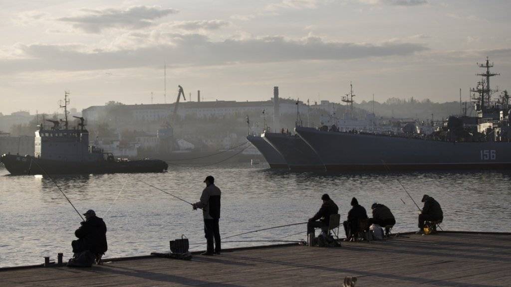 Lokale Fischer vor russischen Militärschiffen im Hafen von Sewastopol auf der Halbinsel Krim. Die NATO hatte ihre praktische Zusammenarbeit mit Russland in Folge der Krim-Annektion im März 2014 ausgesetzt. Nun soll der Dialog wiederbelebt werden. (Archiv)