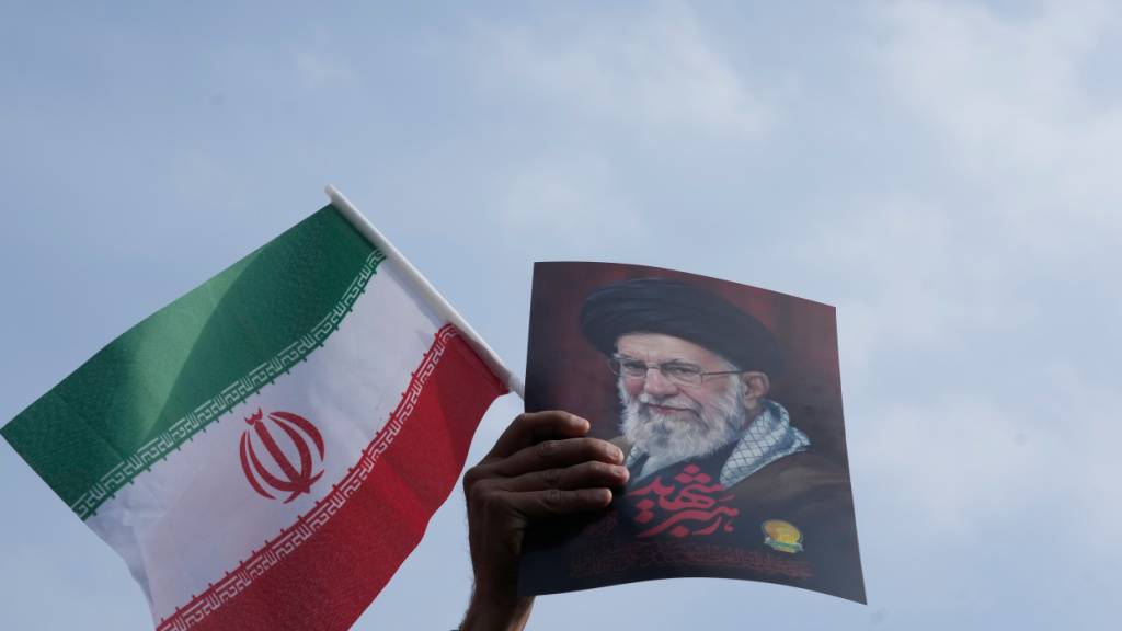 Ein Mann hält eine iranische Flagge und ein Poster des verstorbenen Obersten Führers Chamenei während einer Kundgebung zur Unterstützung seines Sohnes Ayatollah Mojtaba Chamenei, der die Nachfolge seines Vaters als neuer Oberster Führer antritt. Foto: Vahid Salemi/AP/dpa