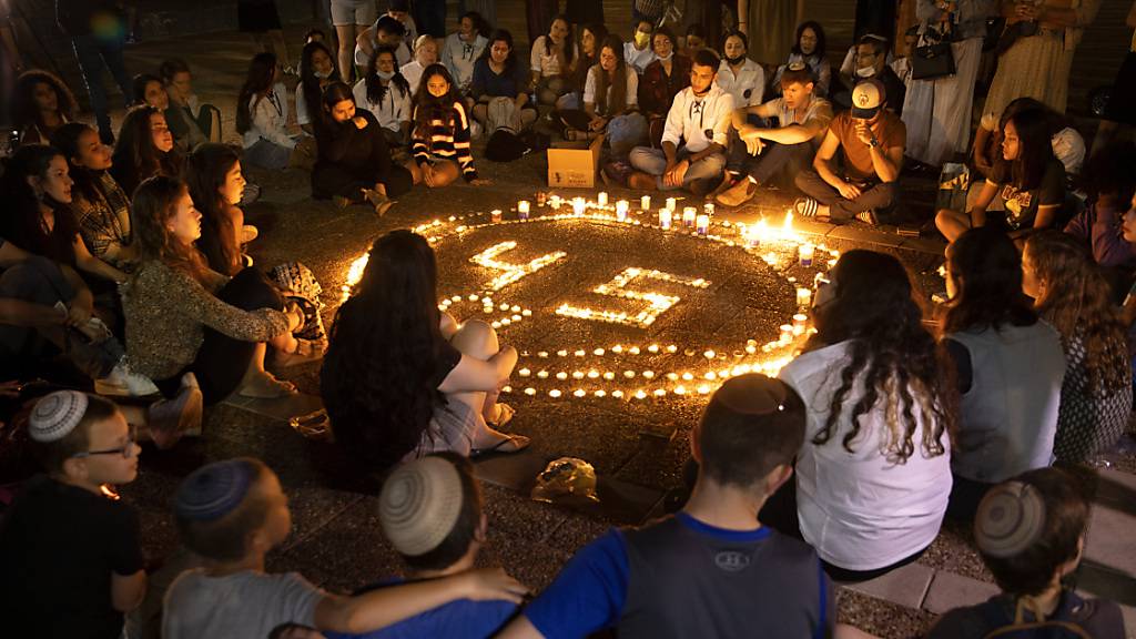 Menschen sitzen während einer Mahnwache um einen Kreis von Kerzen zum Gedenken an die 45 Opfer, die bei einer Massenpanik an einem Wallfahrtsort ums Leben gekommen sind.