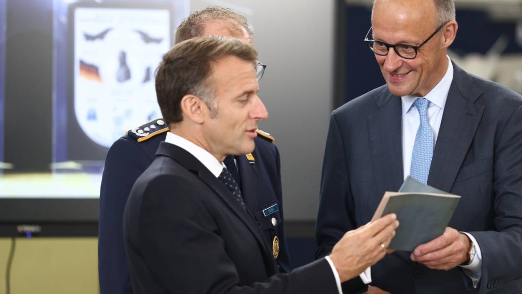 Emmanuel Macron, Präsident von Frankreich und Bundeskanzler Friedrich Merz (r, CDU) halten ein historisches Buch zur Fliegerei in ihren Händen. Foto: Rolf Vennenbernd/dpa